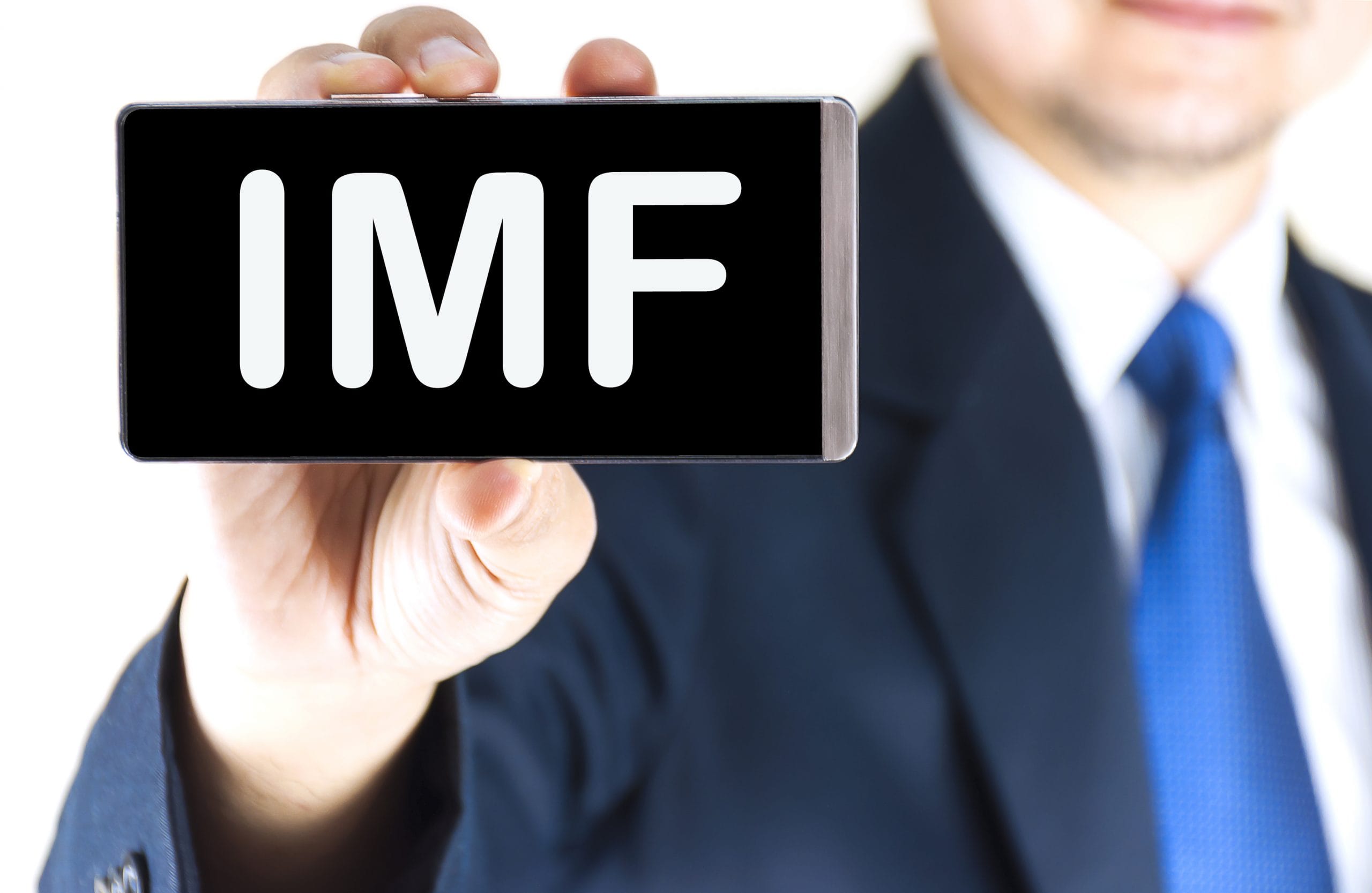 IMF, International Monetary Fund, word on mobile phone screen in blurred young businessman hand over white background, business concept